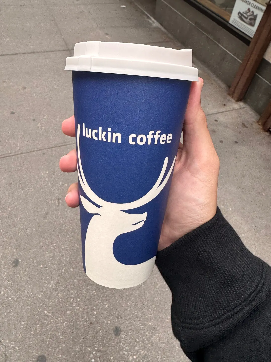 A blue Luckin Coffee takeaway cup held during Mohamad Haidar’s visit to New York.